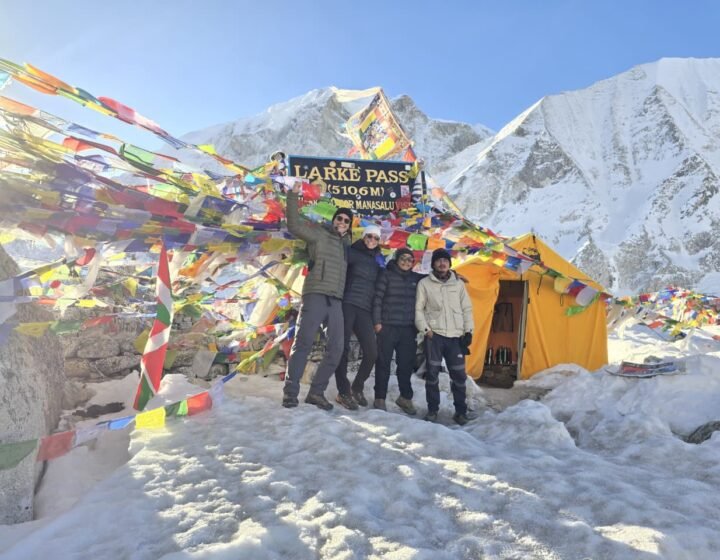 Trekkers celebrating at the Larkya La Pass summit sign during the Manaslu Circuit Trek in Nepal